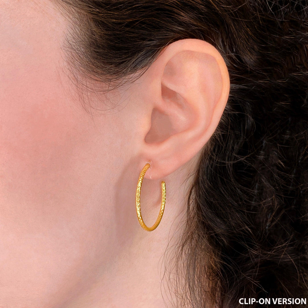 Thin medium sized textured hoop clip on earrings in gold worn on the ear