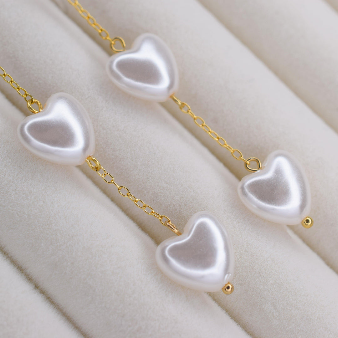 Closeup of the heart shaped pearls on these delicate and dainty bridal gold clip on earrings
