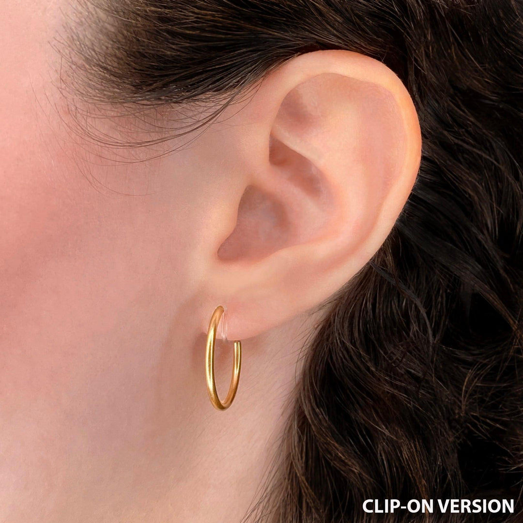Thin small hoop clip on earrings in gold worn on the ear