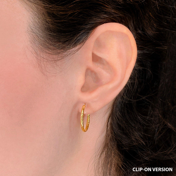 Thin small textured hoop clip on earrings in gold worn on ear